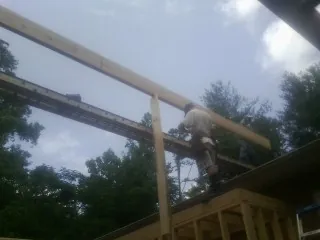 Carpenter setting a ridge beam over a new addition frame — Ice Dam Removal by Roofing Brothers in Pinebluff