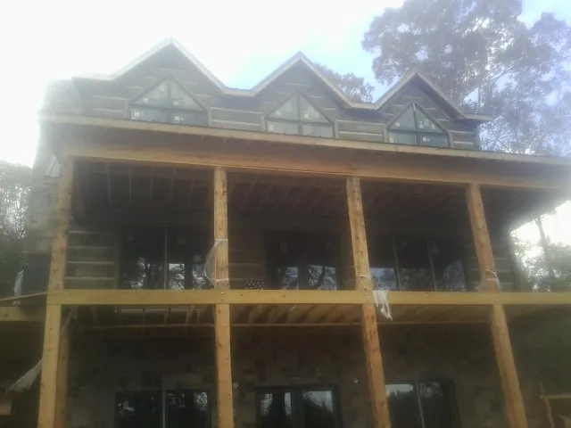 Dormers and porch framing on a large log home under construction — Roof Coating work by our crew in Pinebluff