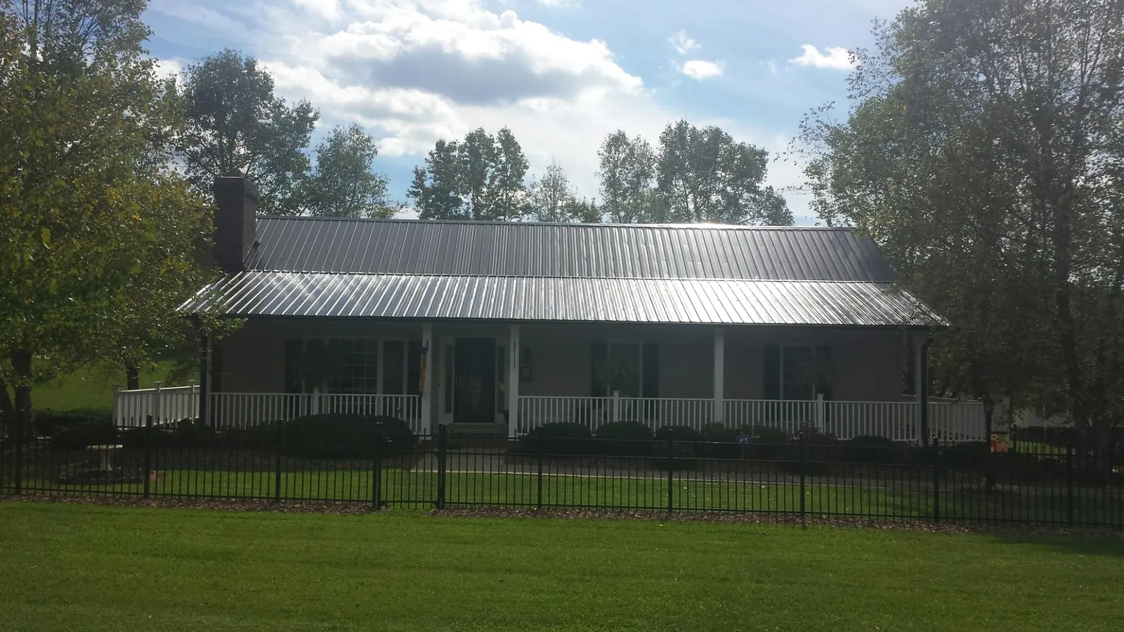 Gray metal roof on a brick ranch with a full width front porch — Gutter Guard Installation work by our crew in Pinebluff