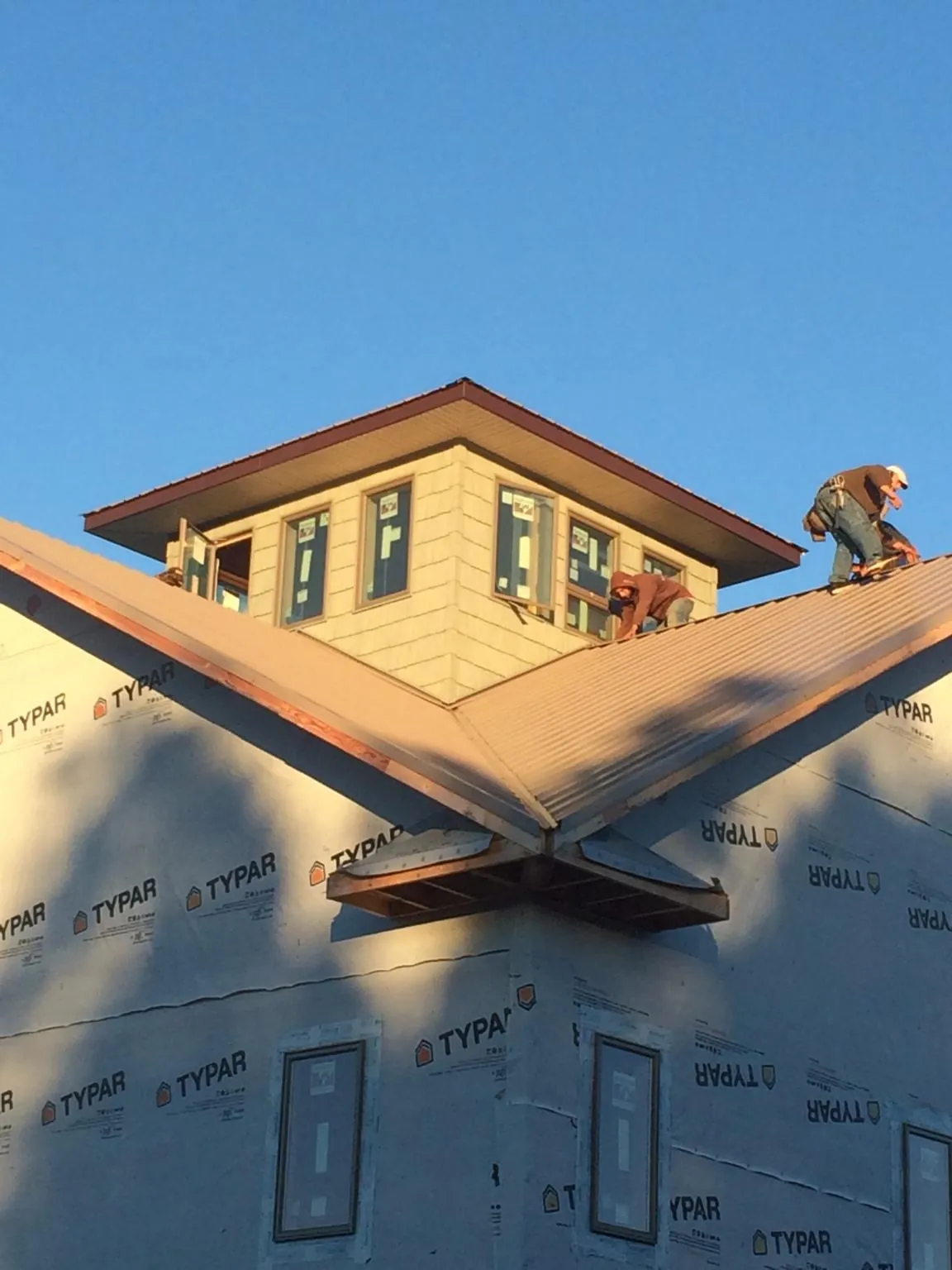 Roofers working around a rooftop cupola on a new metal roof at sunset — Roof Waterproofing in Pinebluff by Roofing Brothers